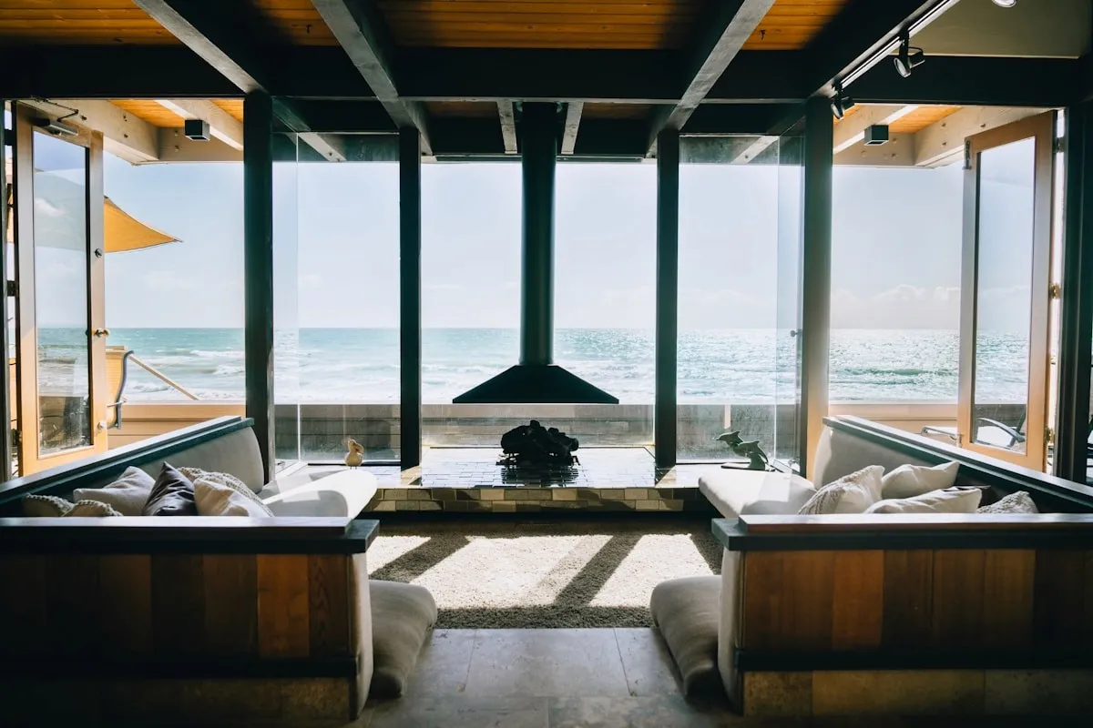 Oceanfront beach house living room with floor-to-ceiling windows and views across the water