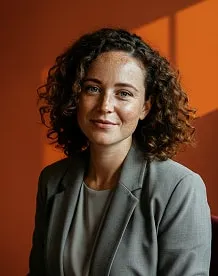 Portrait of a lead advisor in a gray blazer against a warm orange background